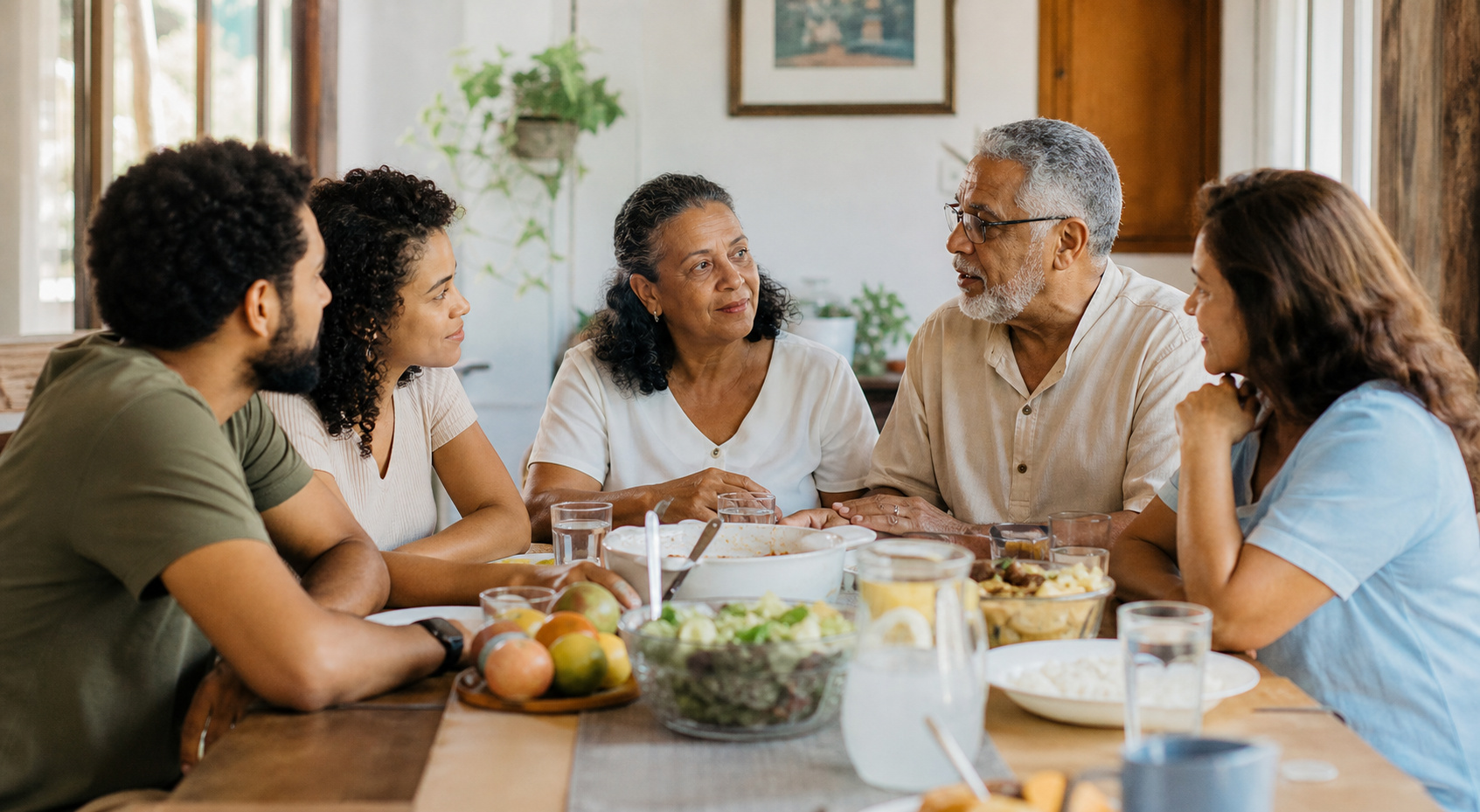Família de diferentes gerações conversando com respeito ao redor de uma mesa.
